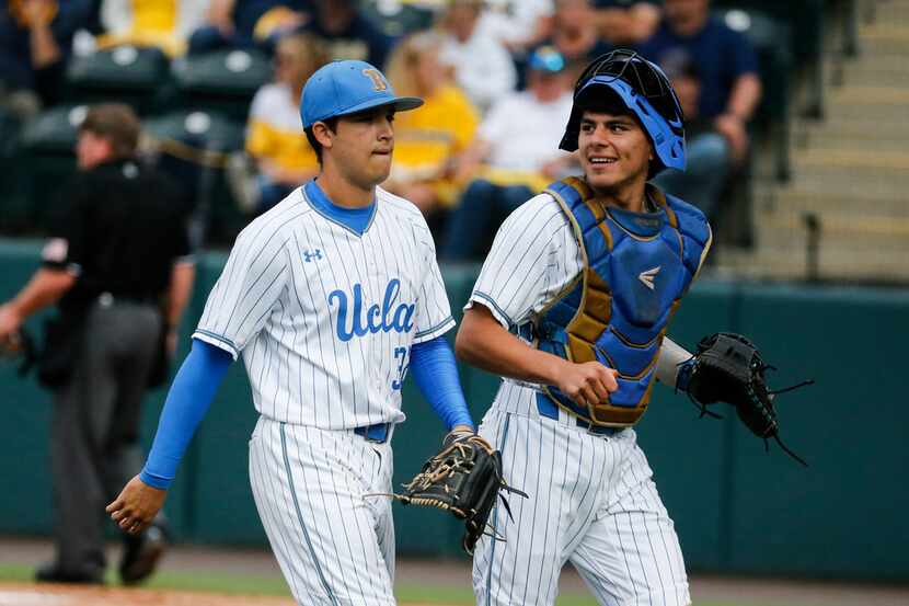UCLA pitcher Ryan Garcia, left, and catcher Noah Cardenas walk off the field after the top...