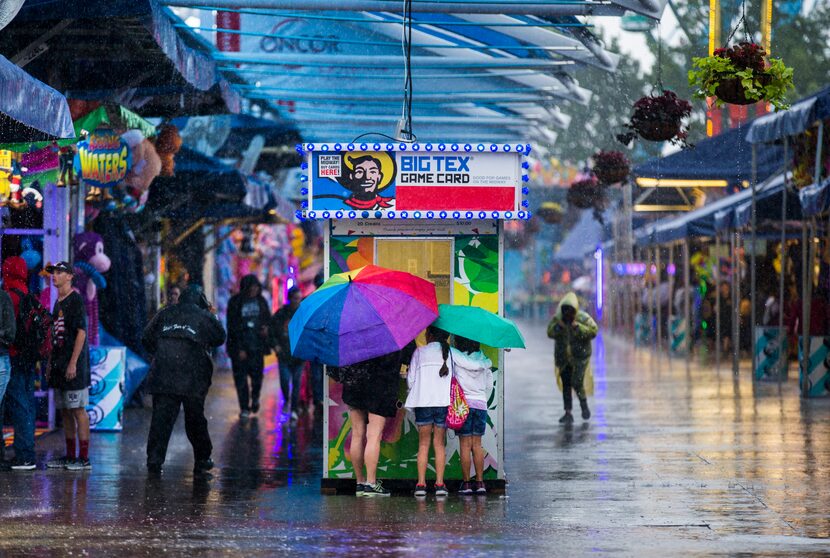 Julie Fernandez, Catalina Fernandez, and Kariss Fernandez, 10, buy game cards in the rain in...