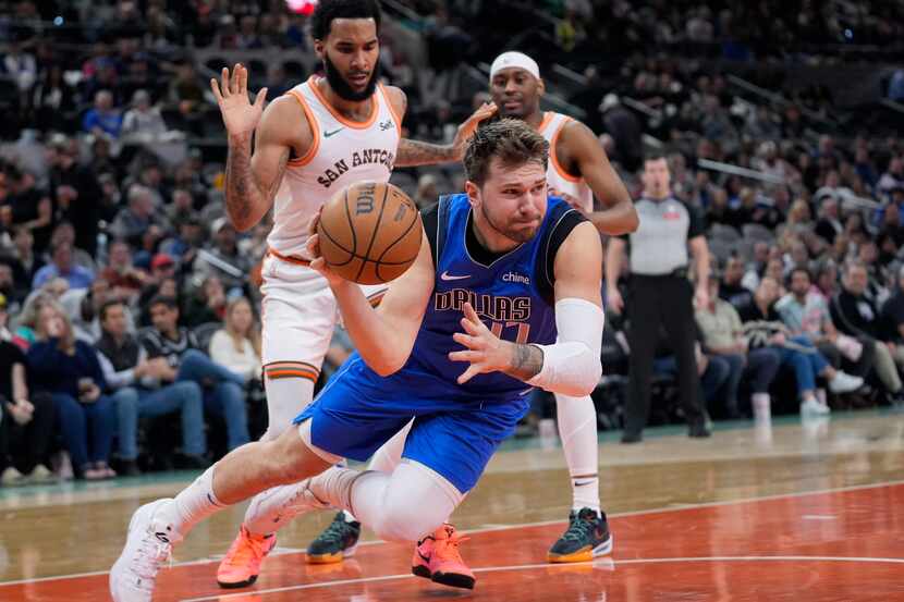 Dallas Mavericks guard Luka Doncic (77) tries to pass the ball as he is tripped during the...