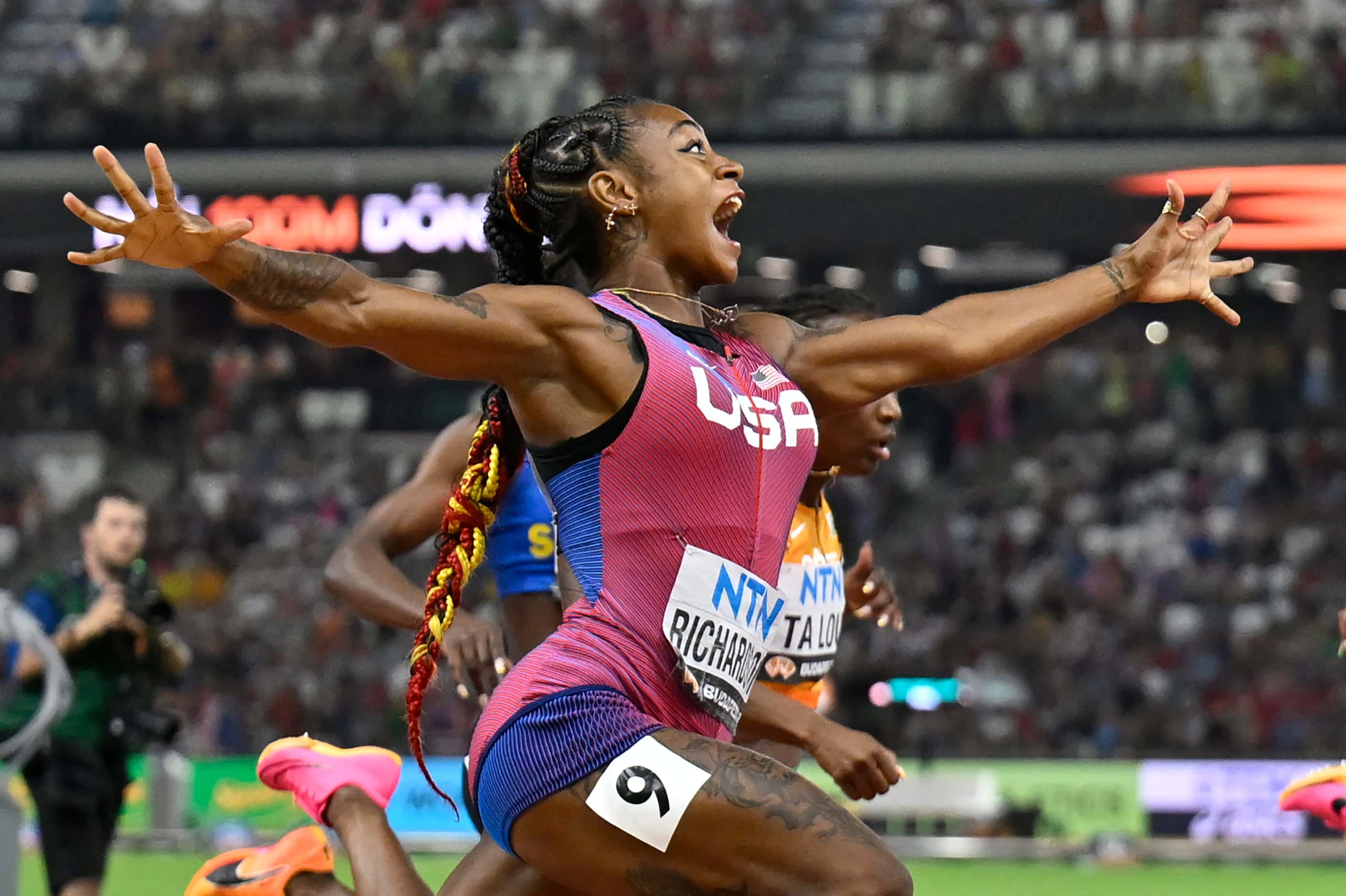 Sha'Carri Richardson, of the United States, spreads her arms as he crosses the line to win...