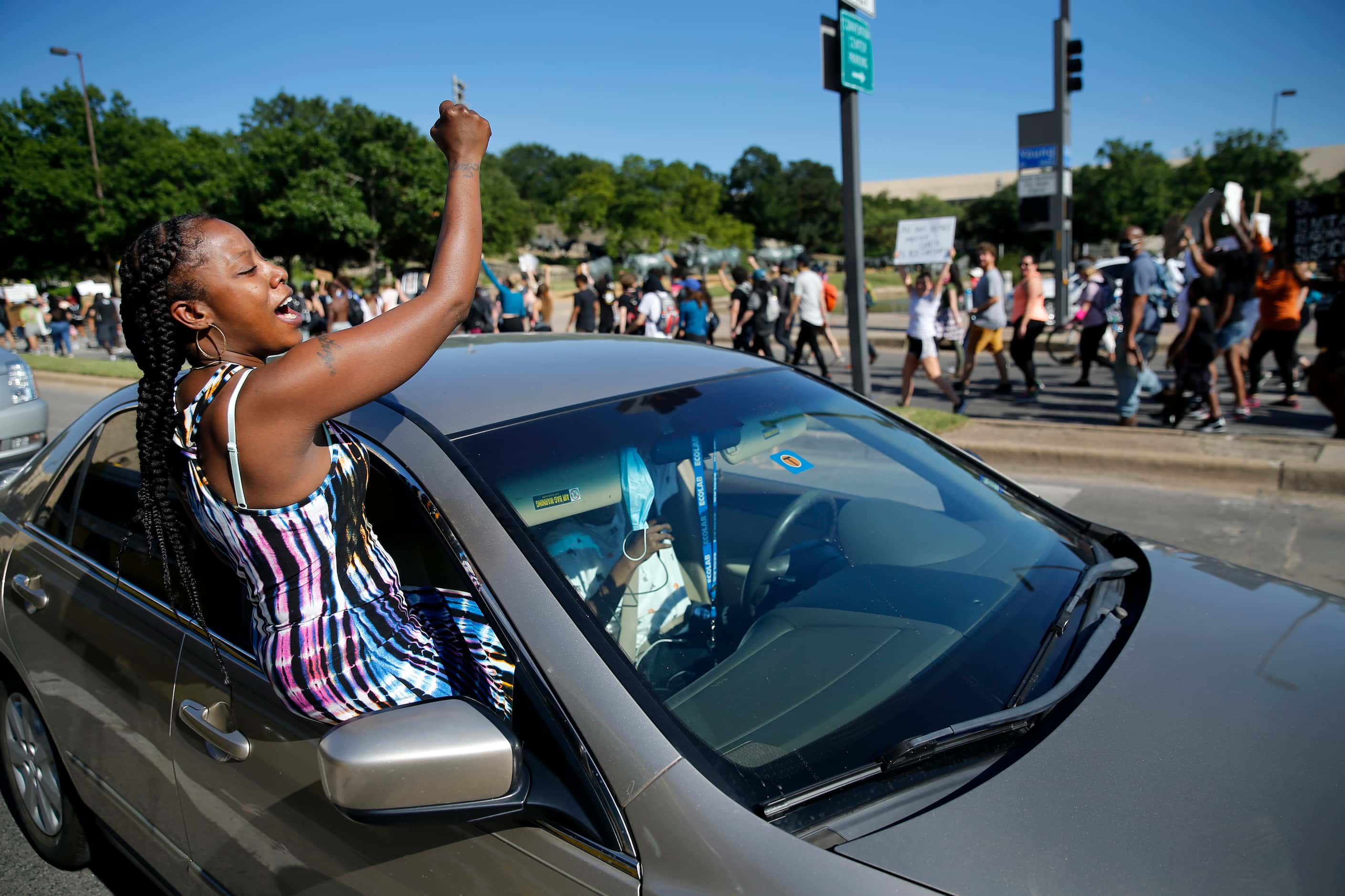 Angel Brown of Dallas crawls out of the car window to support Black Lives Matter supports...