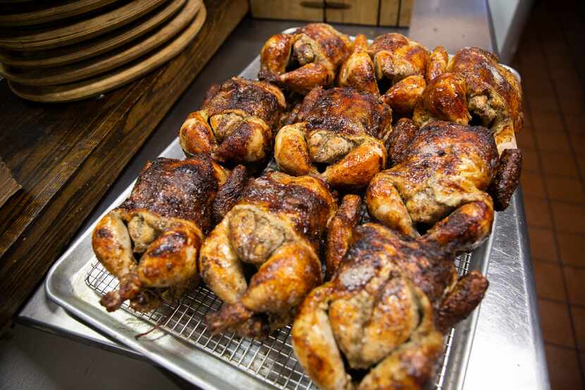 The pollo a la brasa (Peruvian roasted chicken) comes out of the oven at the Brasa Bar and...