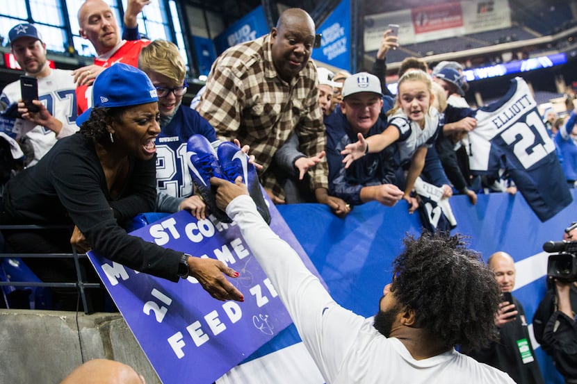 Dallas Cowboys running back Ezekiel Elliott (21) hands his shoes to a young fan after an NFL...