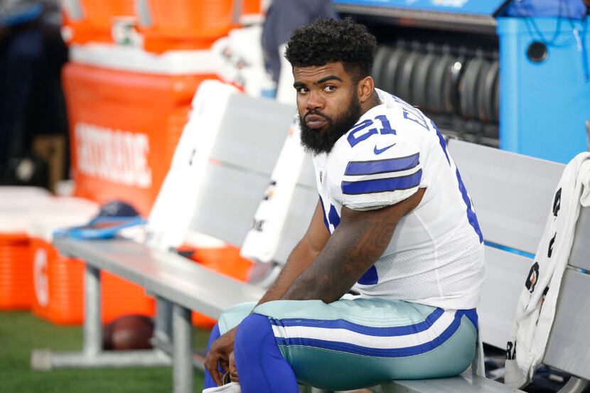 Dallas Cowboys running back Ezekiel Elliott sits  on the bench during the first half of a...