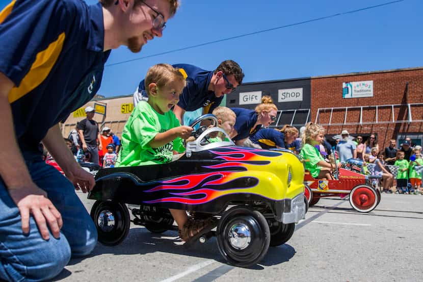 Royce Mancini, 3, races from the starting line with help from volunteer Jonah Branch, left,...