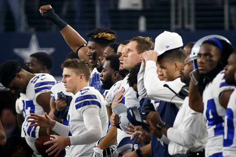 Dallas Cowboys defensive tackle David Irving raises his fist as players and coaches stand at...