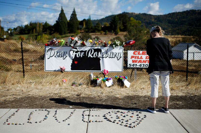 A woman visits a makeshift memorial near the road leading to Umpqua Community College,...