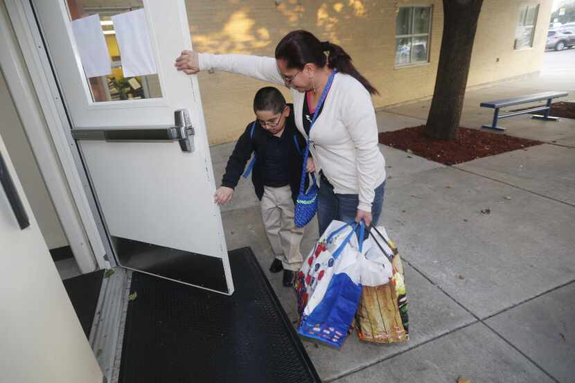 Samuel Garcia, 6, gets help with the door from his mother Irma Garcia, on the first day of...
