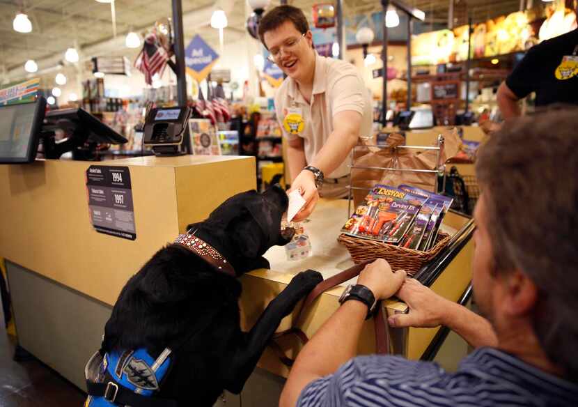 
Jason Morgan’s service dog Rue takes a receipt from a cashier at Market Street in McKinney....