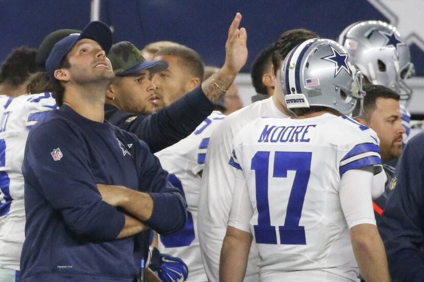 Dallas Cowboys quarterback Kellen Moore (17) walks past injured quarterback Tony Romo (9) on...