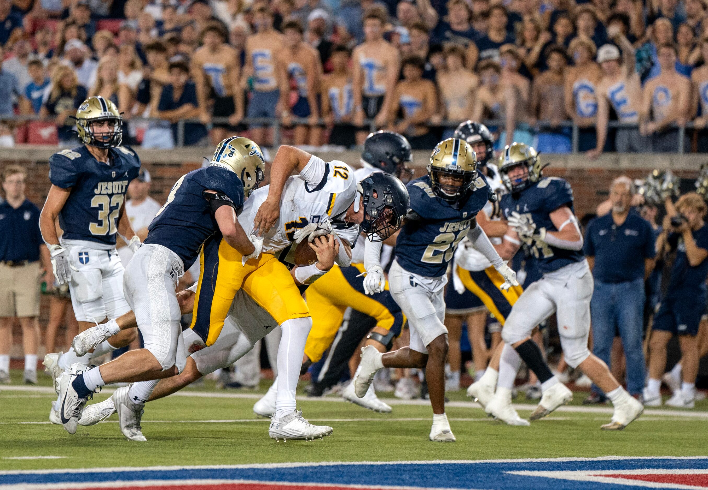 Highland Park senior quarterback Warren Peck (12) powers past Jesuit senior linebacker Bobby...