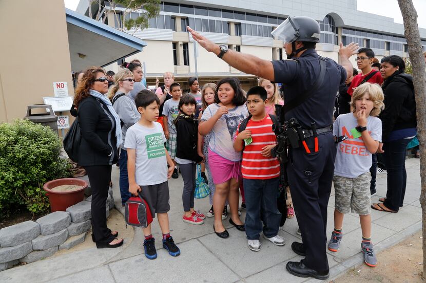 A Santa Monica police officer leads children from Citizens of the World School in Los...