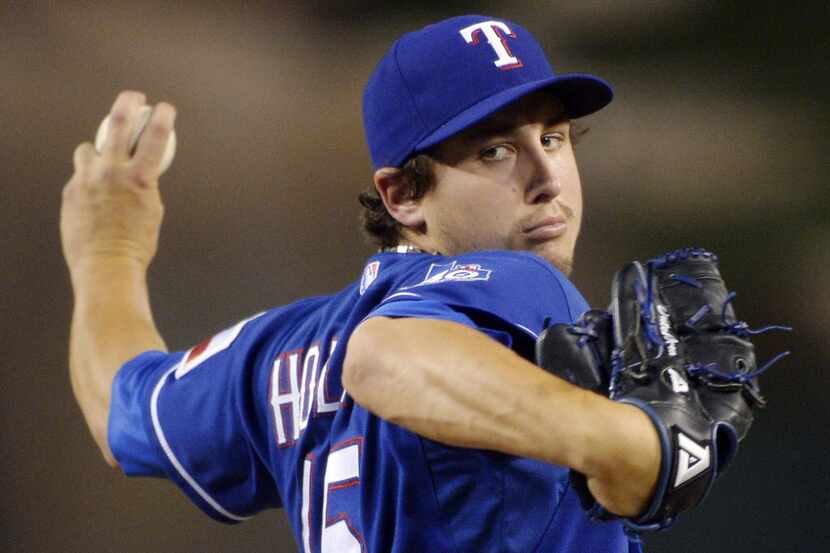 The Texas Rangers' Derek Holland waves as he leaves the game after giving up a solo home run...