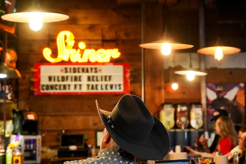 Guests watch from the bar during a benefit concert at Sideways BBQ on Monday, March 18,...