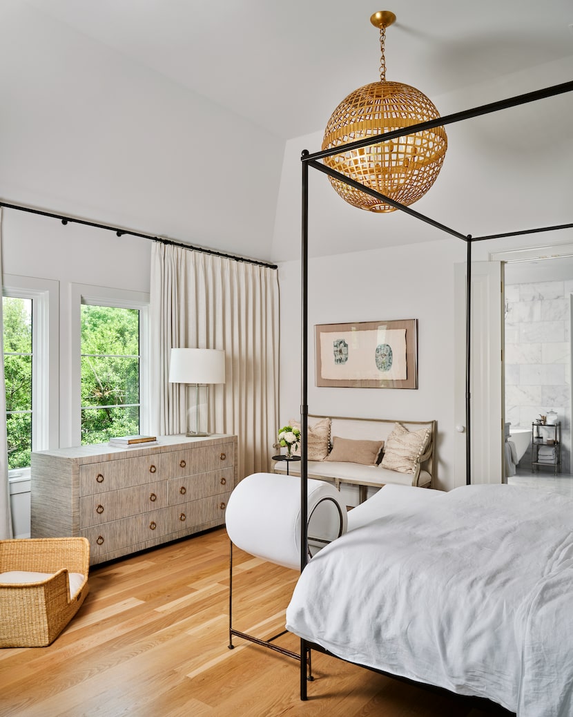 A canopy bed in a bedroom is placed along one side with a dresser opposite.