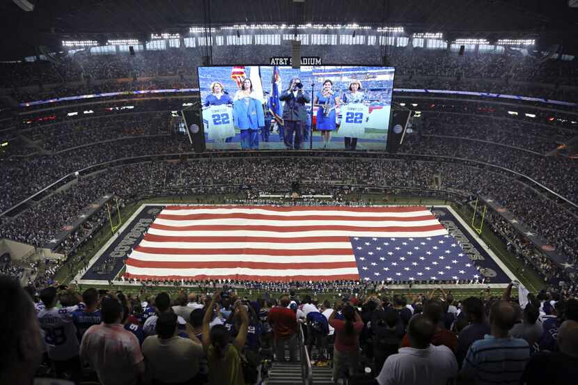 A large American flag is held over the field during the national anthem at the Dallas...