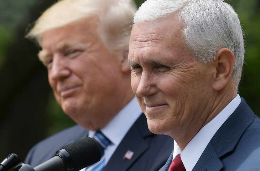 US Vice President Mike Pence (R) speaks while standing next to US President Donald Trump...
