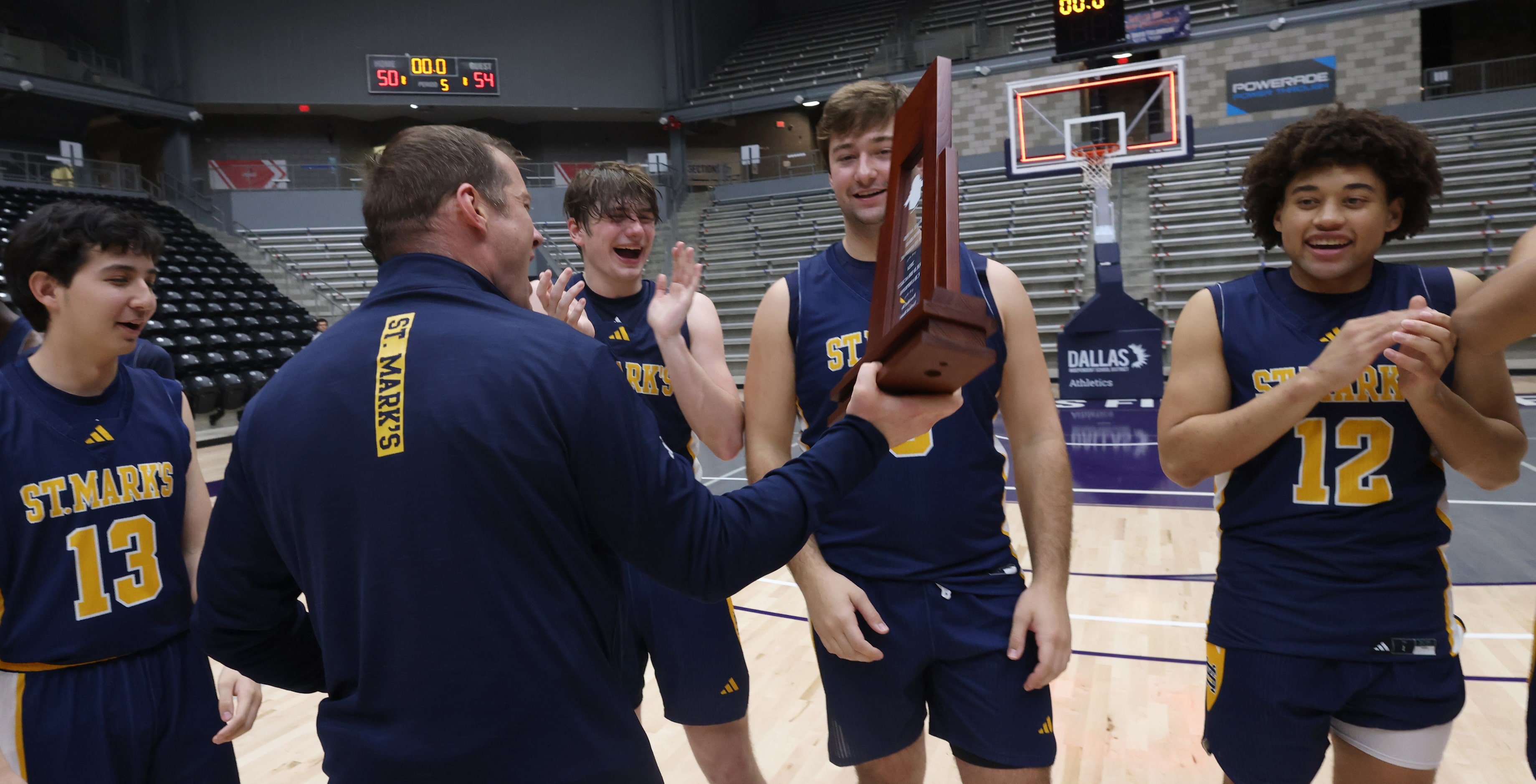 St. Mark's head coach Greg Guiler, (back to camera) reads the inscription on the tournament...