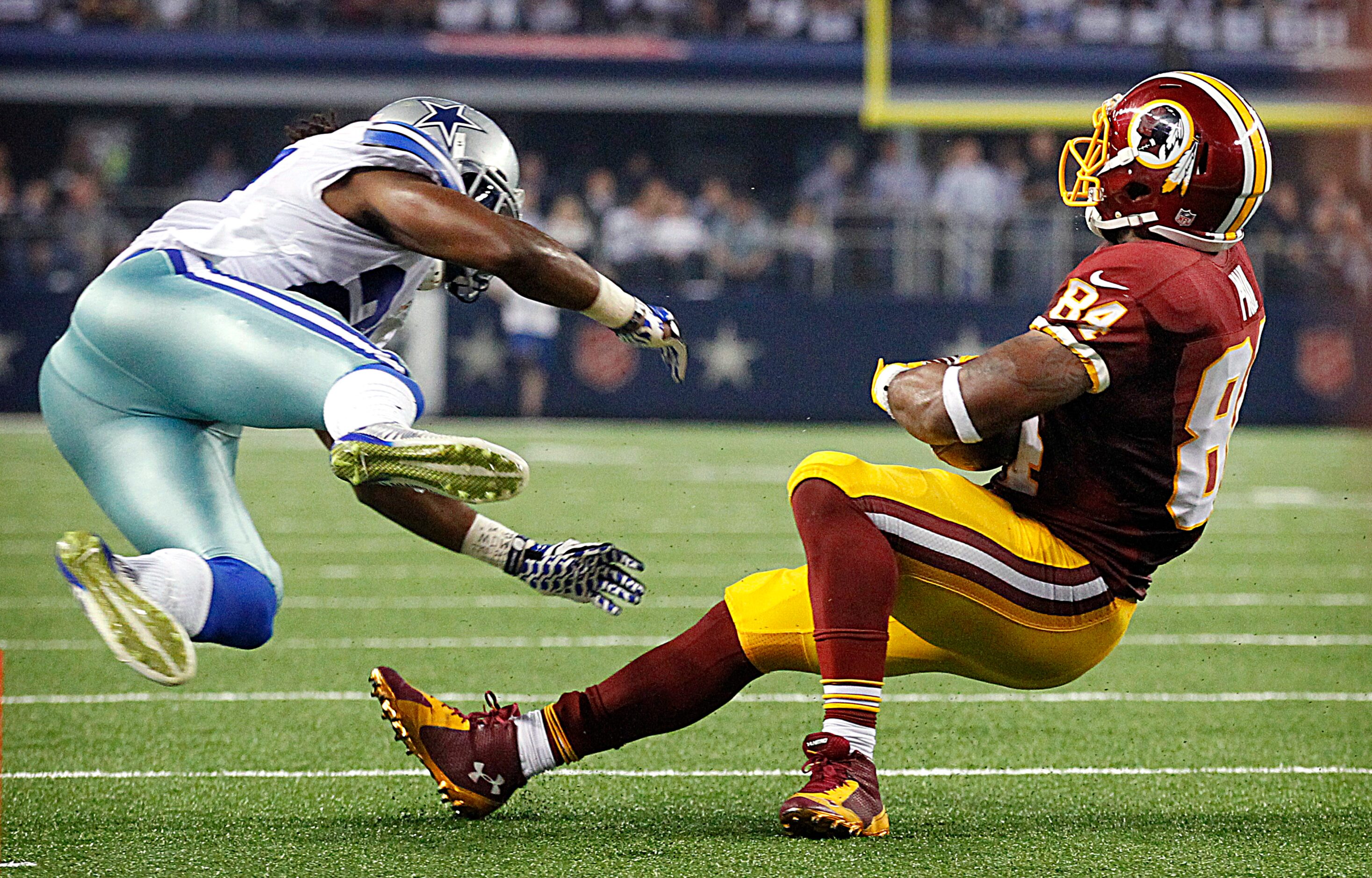 Dallas Cowboys strong safety J.J. Wilcox (27) goes flying after spinning around Washington...