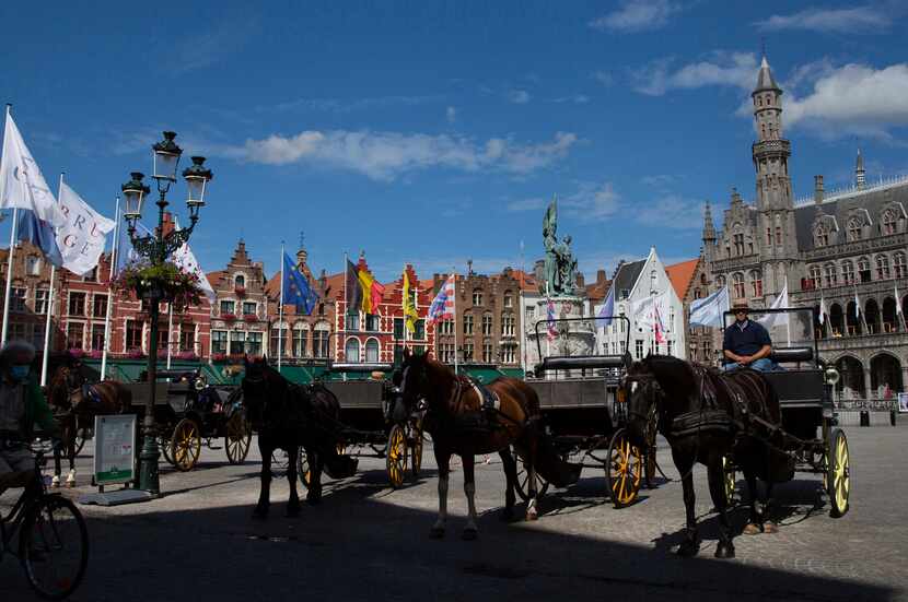 Horse and carriage tour operators wait in the center of Bruges, Belgium, as summer tourism...