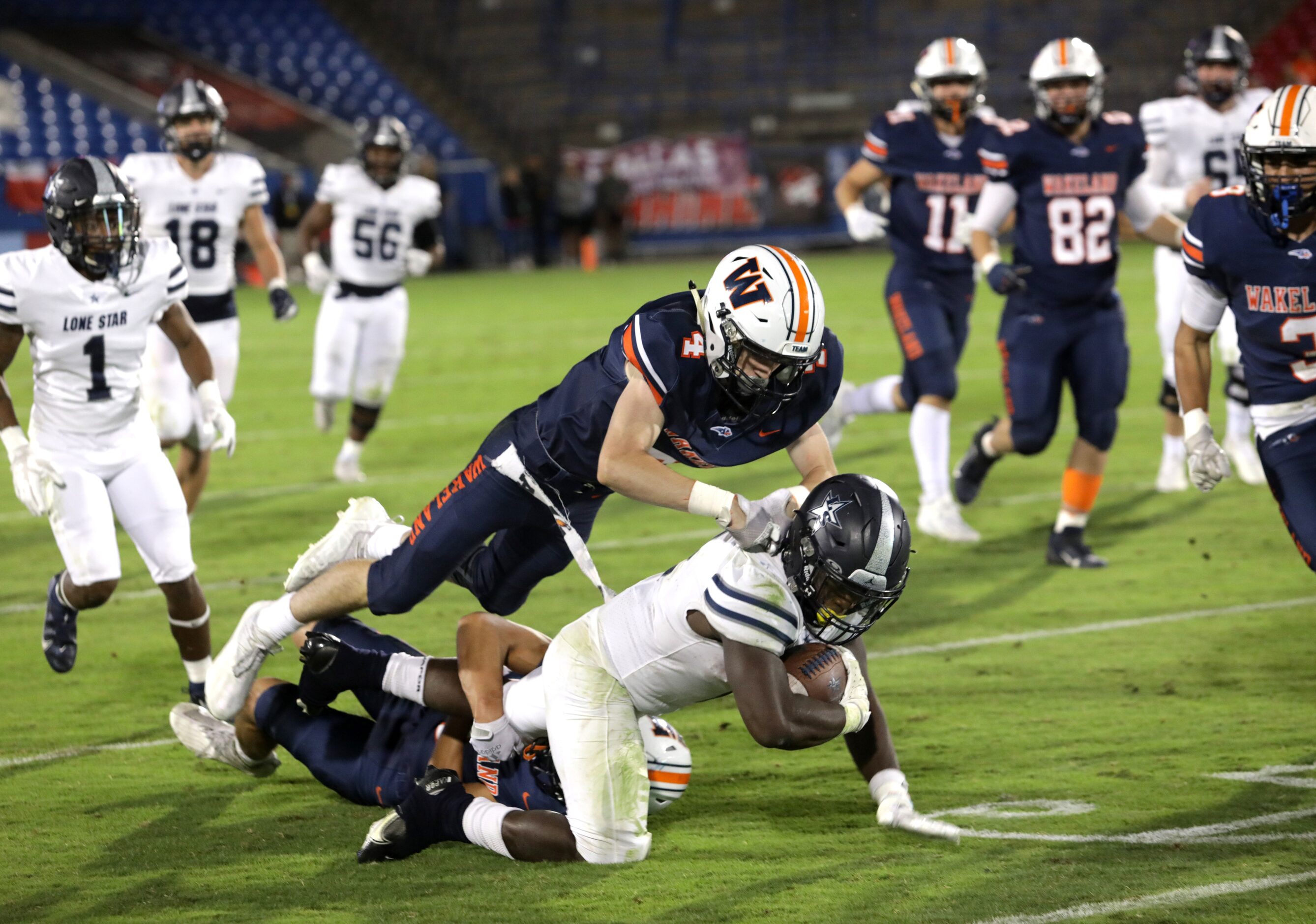 Lone Star player #2, Ashton Jeanty, is tackled by Wakeland players #4, Gus England, and #1,...