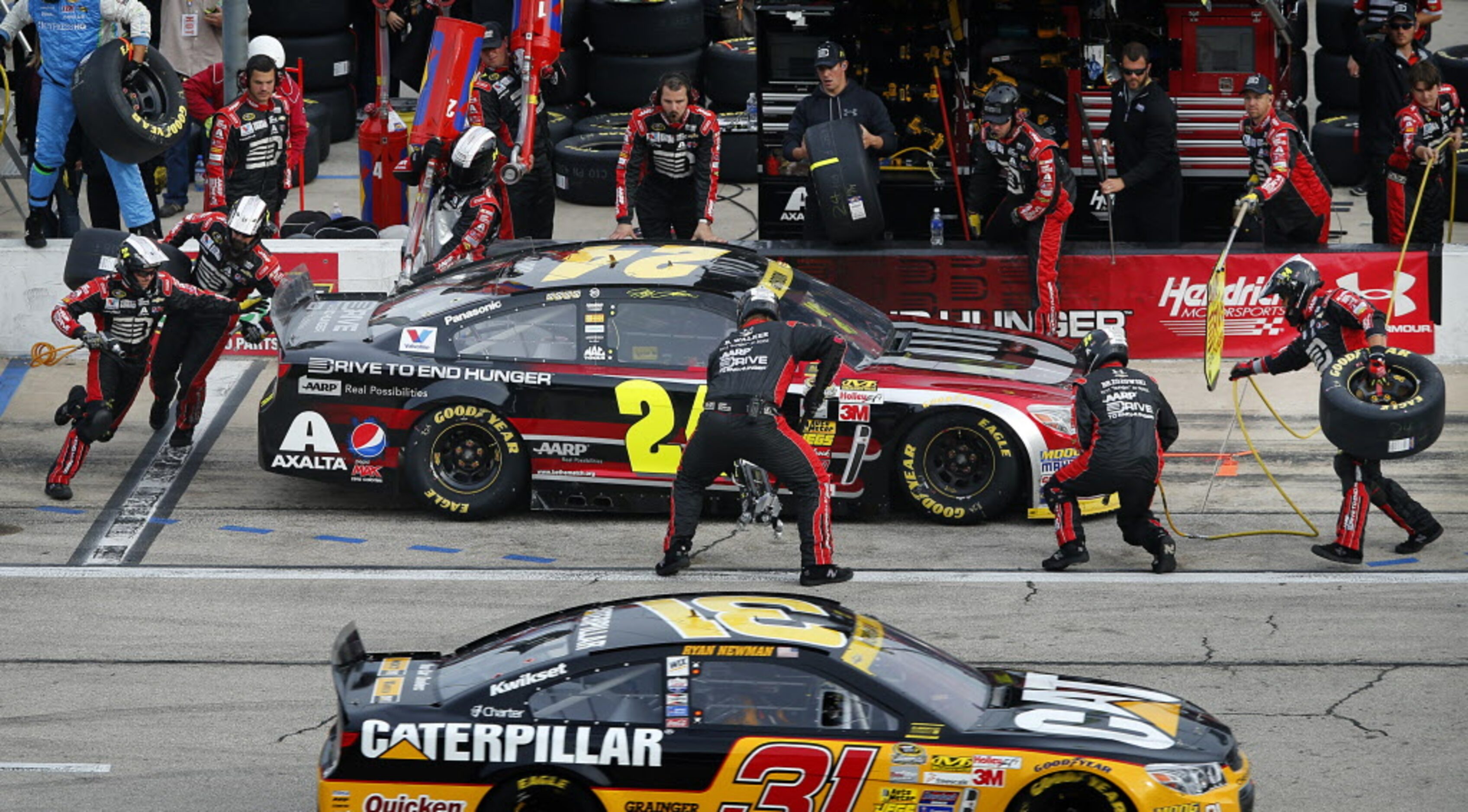 Sprint Cup Series driver Jeff Gordon (24) receives a four-tire change during a pit stop in...