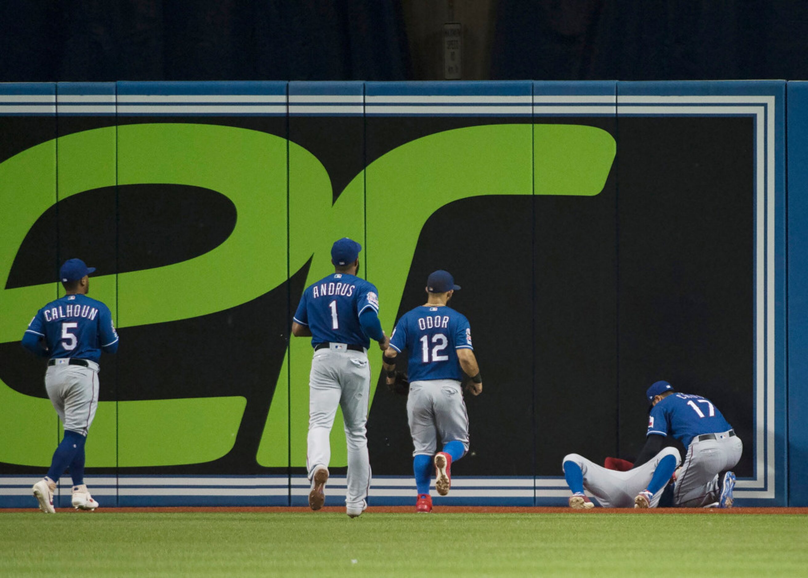 Texas Rangers center fielder Delino DeShields, second right, lays hurt after making a catch...