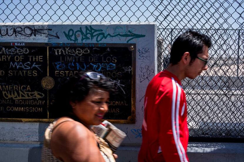 Pedestrians pass a placard marking the dividing line of the US-Mexico Border on the Cordova...