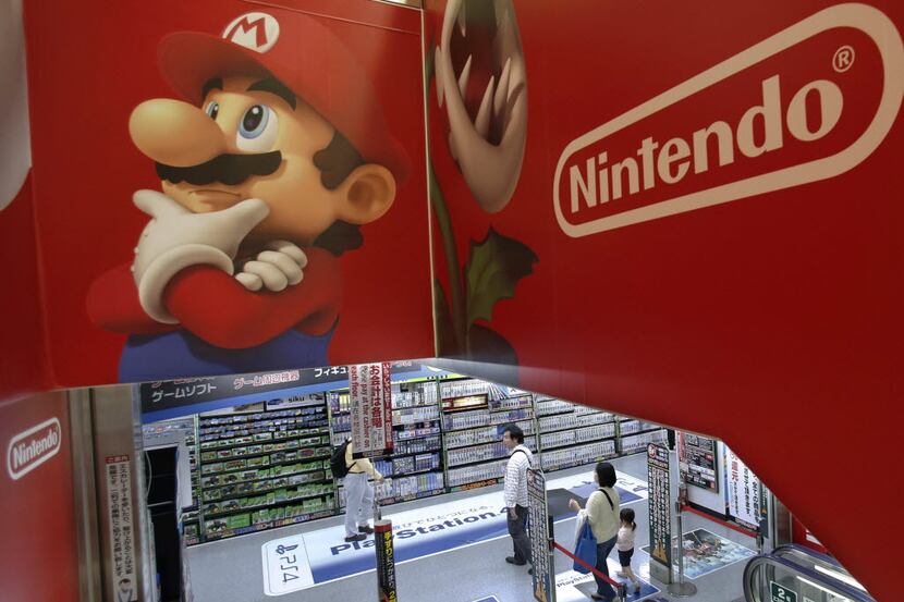 FILE - In this May 7, 2014, file photo, shoppers walk under the logo of Nintendo and Super...