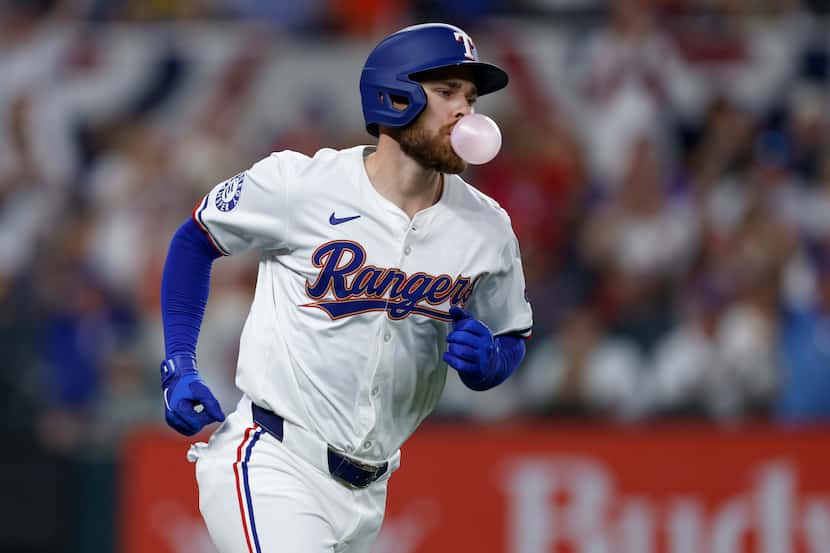 Texas Rangers first baseman Jared Walsh (21) blows a bubble as he rounds the bases after...