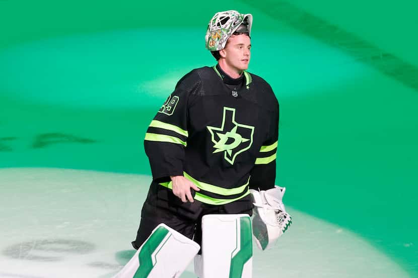 Dallas Stars goaltender Jake Oettinger (29) holds a puck to toss over the glass to fans as...