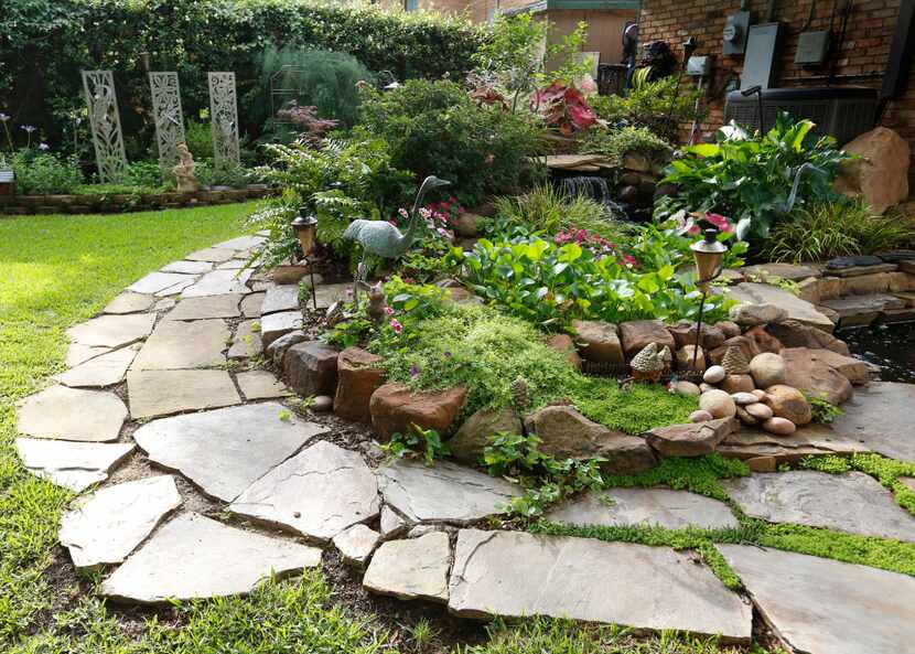 Kimberly Atchley placed the stones and planted the flowers in her backyard pond at her...
