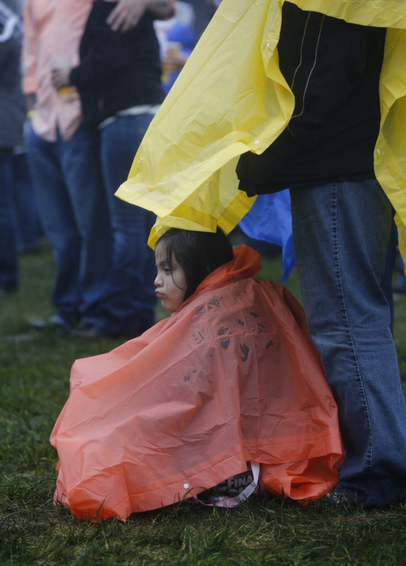 Catherine Acosta, 6, gets shelter from the rain under her mother, Carmen Acosta's raincoat...