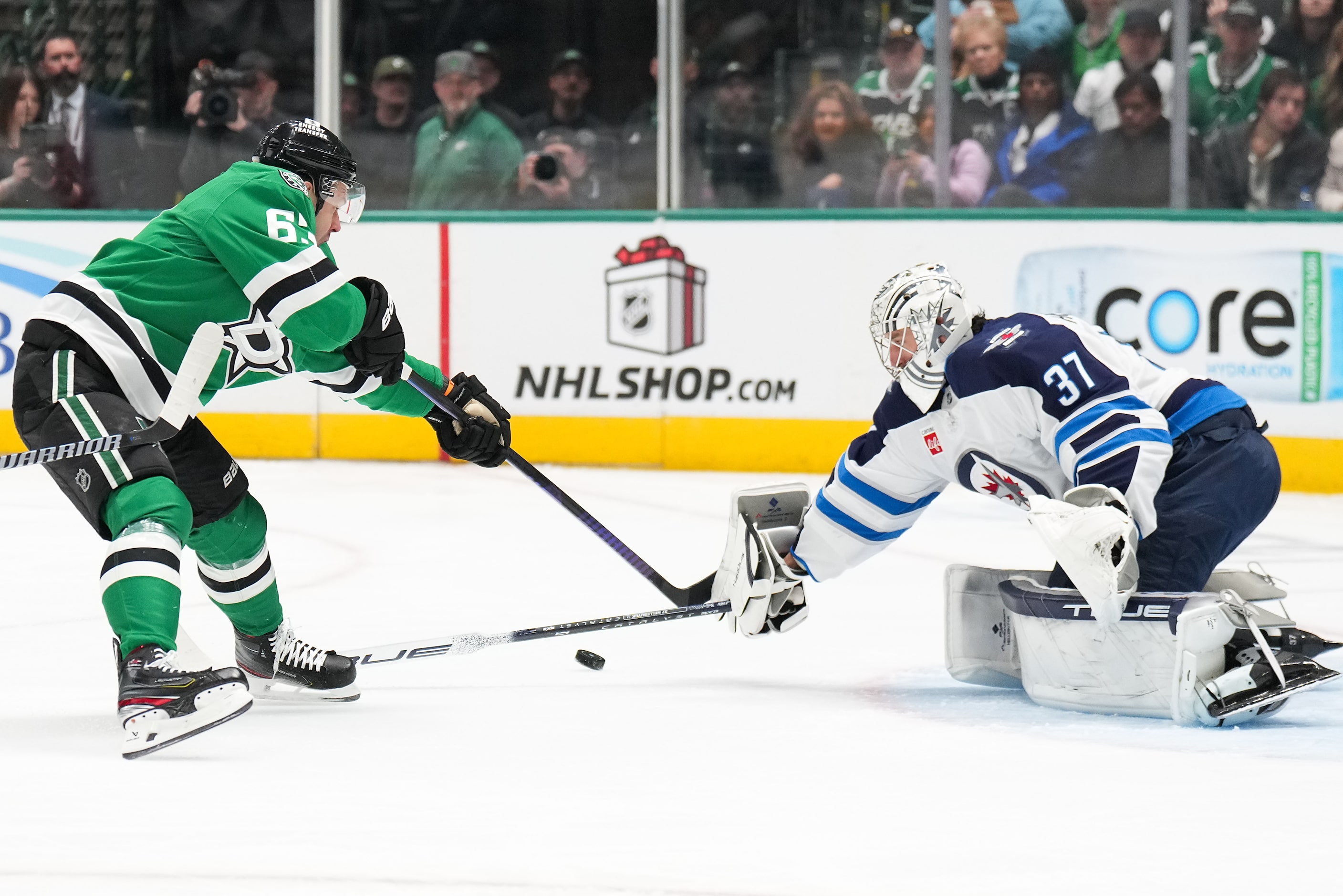 Winnipeg Jets goaltender Connor Hellebuyck (37) makes a save against Dallas Stars right wing...