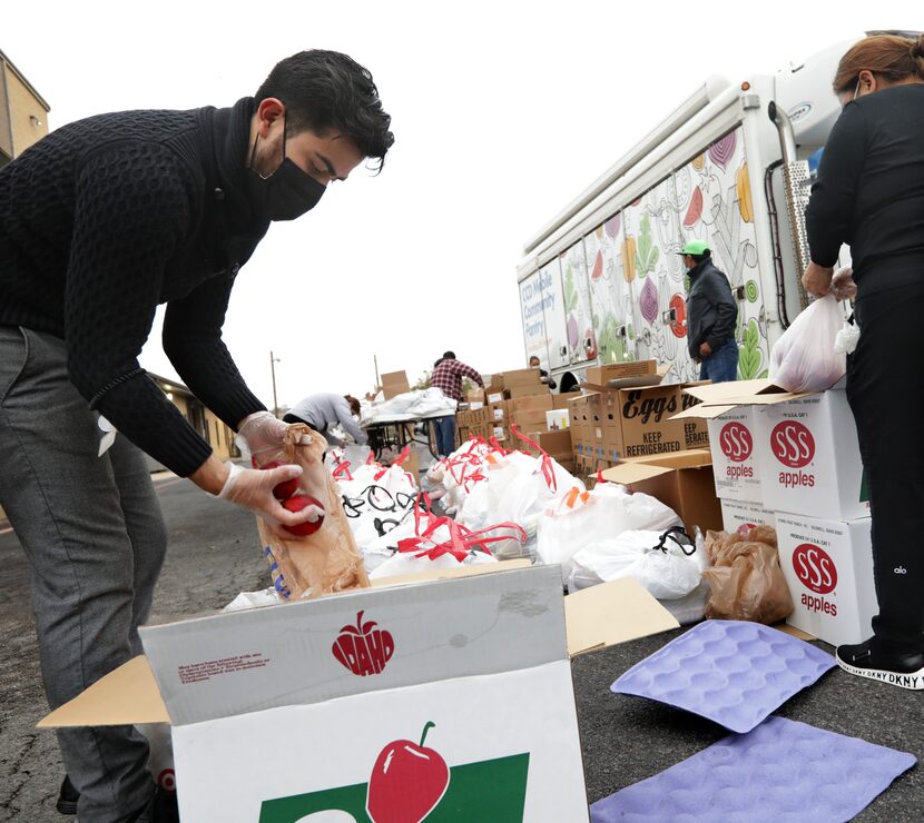 Margarito "Jr." Garcia, left, helps prepare food and essentials bags to distribute to the...