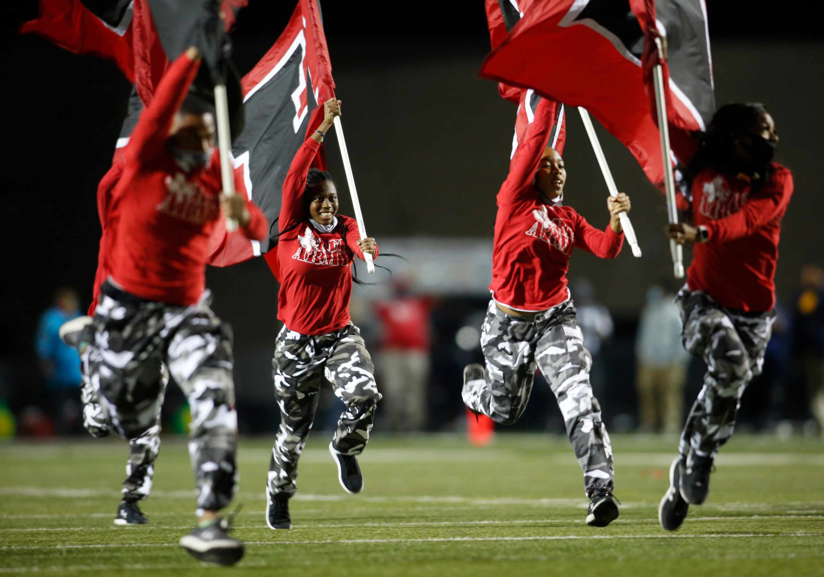 Members of the Cedar Hill Longhorns Red Army Flag Runners bolt across the field in...