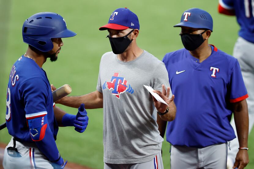 Texas Rangers manager Chris Woodward (middle) wears a mask as he visits with outfielder...