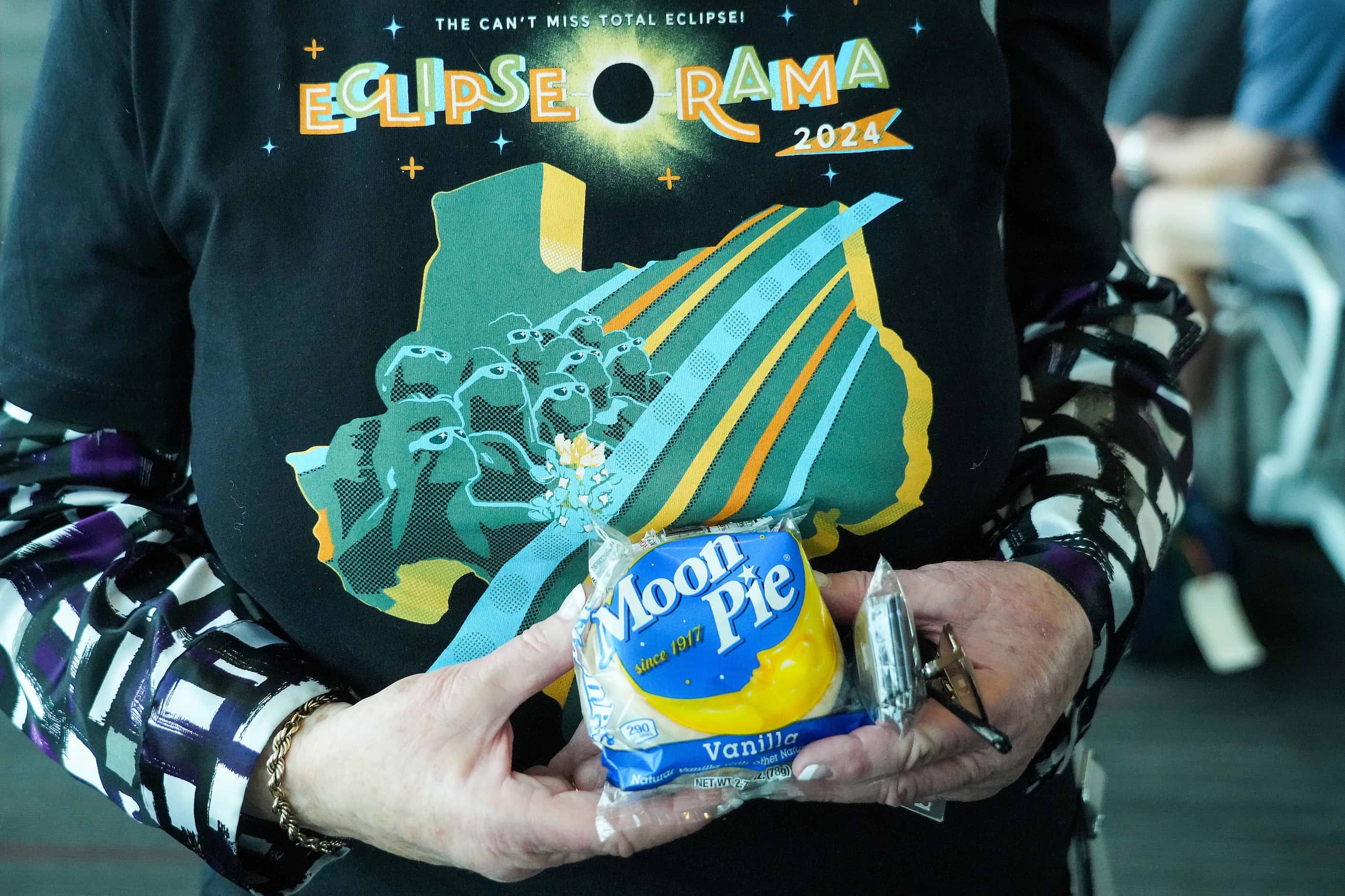 Bonnie Shatun holds a moon pie and wears an t-shirt promoting Eclipse-O-Rama before boarding...