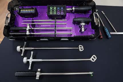 Courtney displays surgical caddies with screws and tools used during spine procedures in his...
