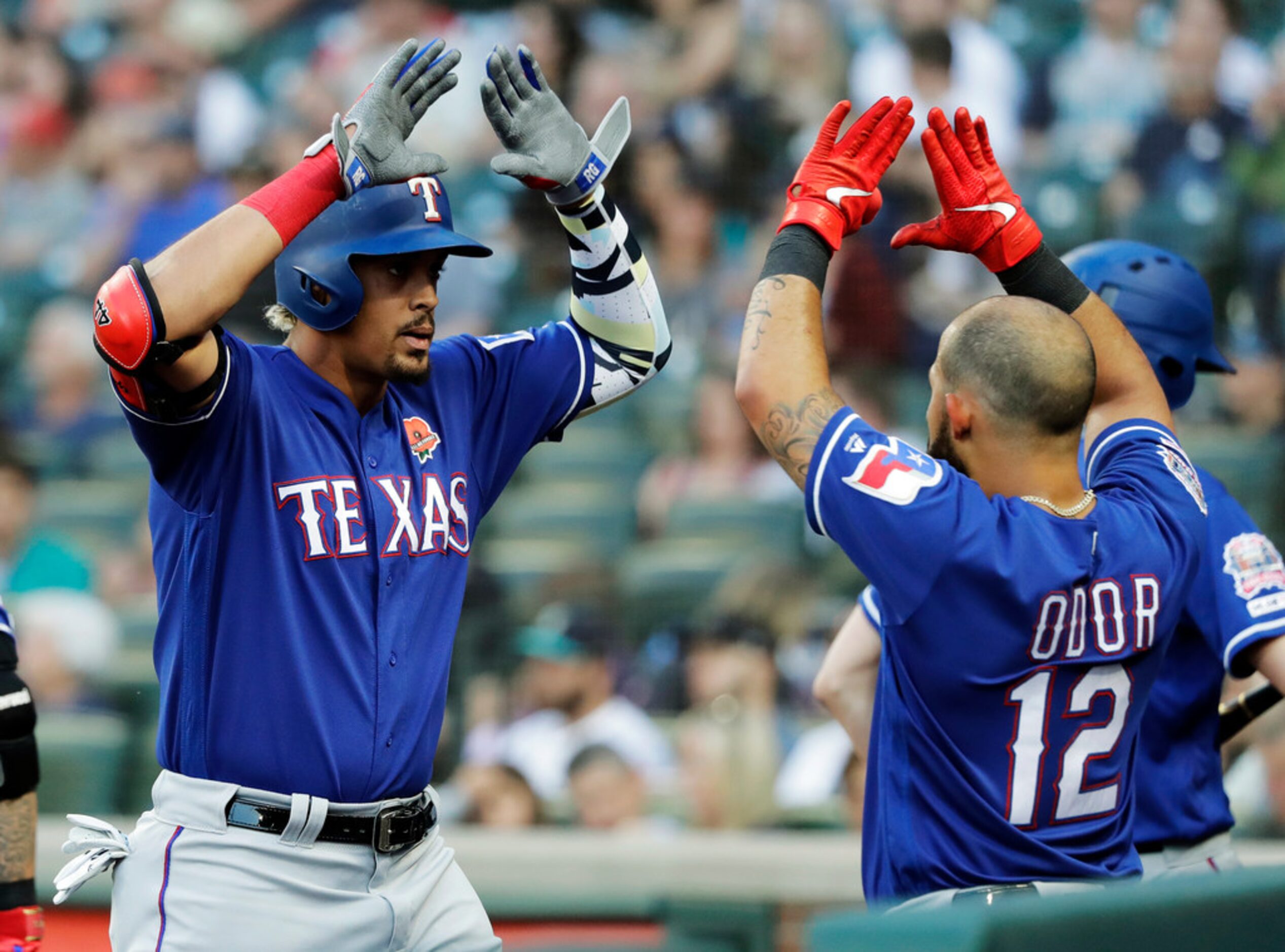 Texas Rangers' Ronald Guzman, left, is greeted in the dugout by Rougned Odor after Guzman...