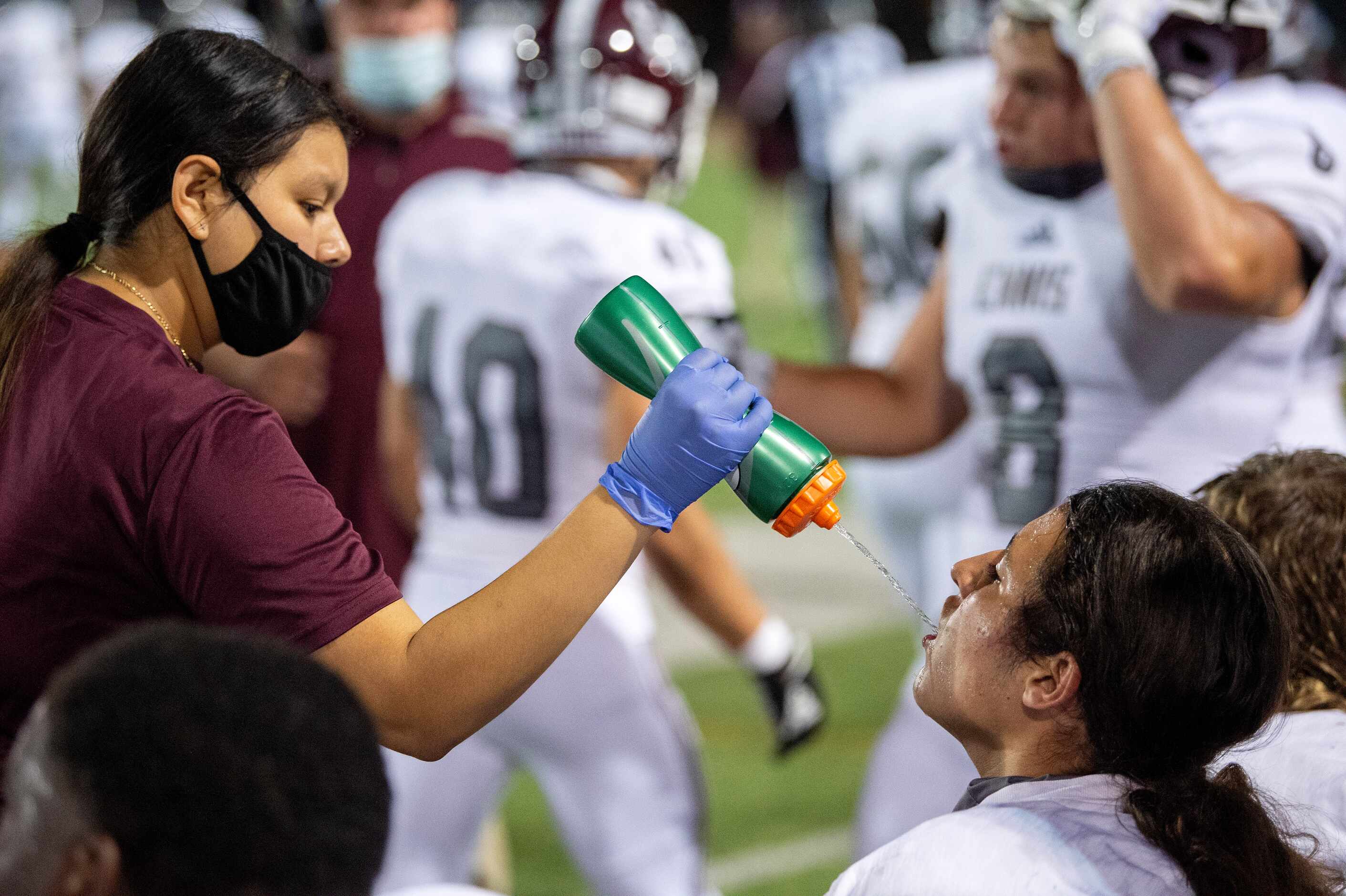 Ennis senior trainer Jacqueline Ceida squirts water into the mouth of sophomore lineman...