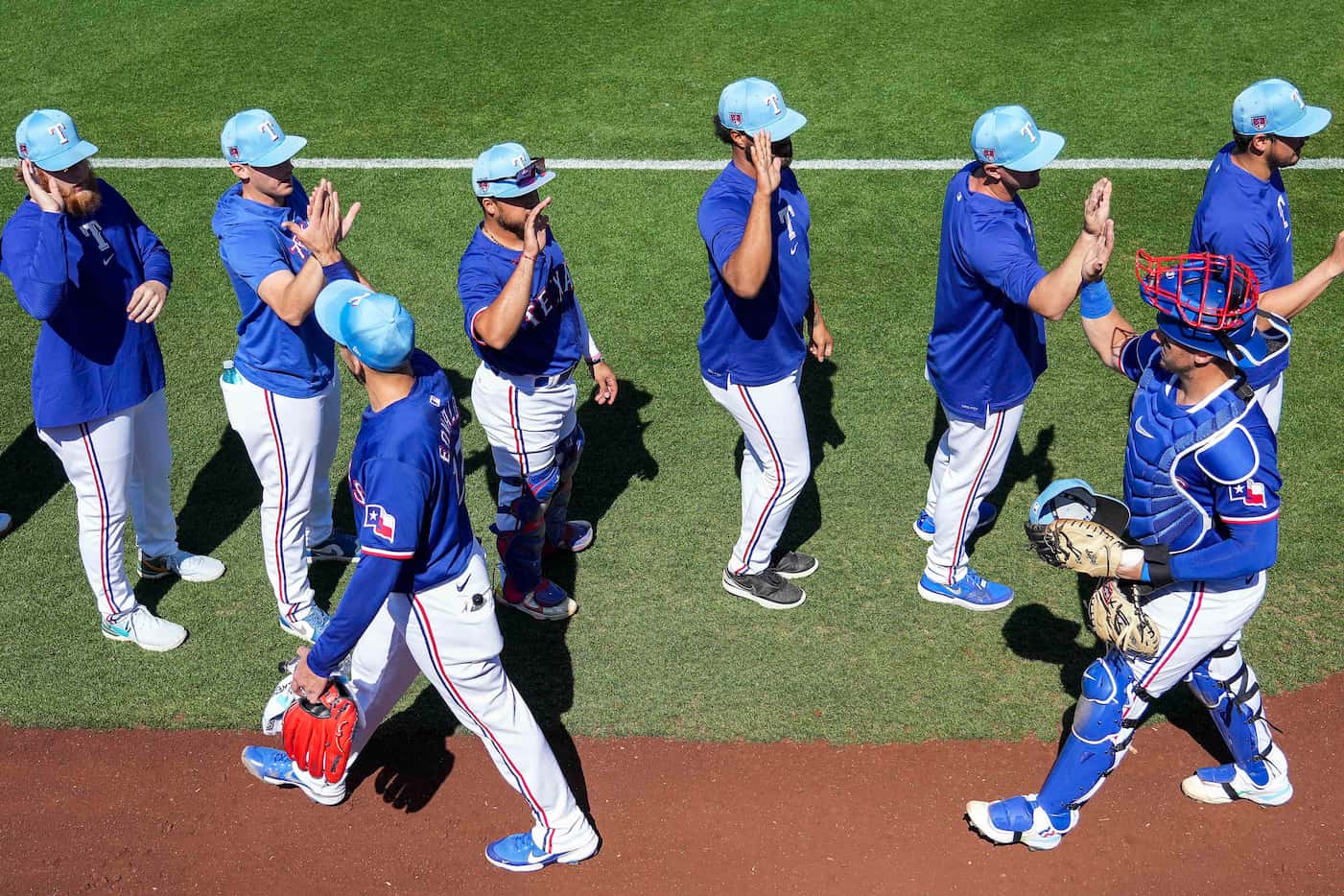 Texas Rangers pitcher Nathan Eovaldi and catcher Andrew Knizner high five teammates before a...