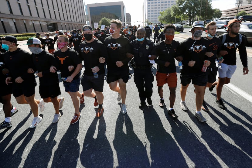 Members of the Austin police department march with members of the University of Texas...