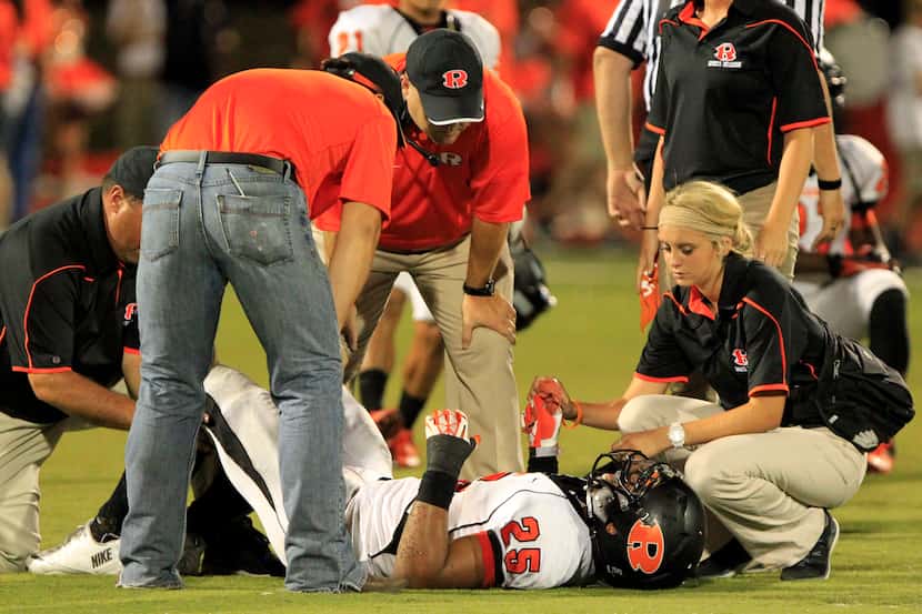 Coaches and trainers attend to Rockwall High RB Chris Warren (25), after he was injured...