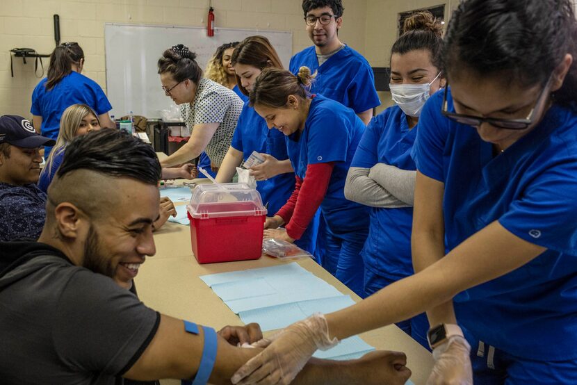 Luis Garibay has his blood drawn by wife Miriam Castaneda, a patient care technician...