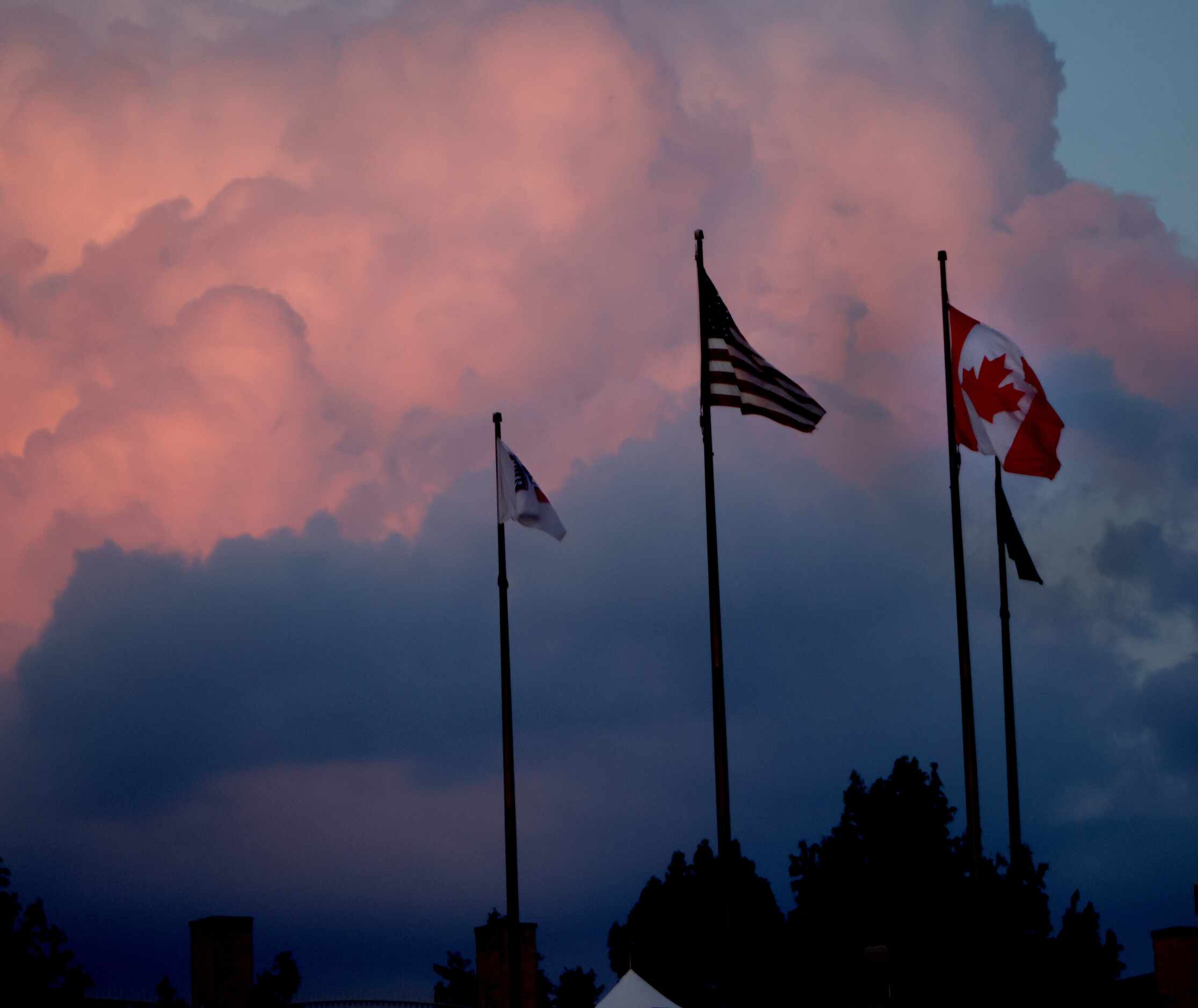 The American flag flies next to the Canadian flag at sunset during the first half of the FC...