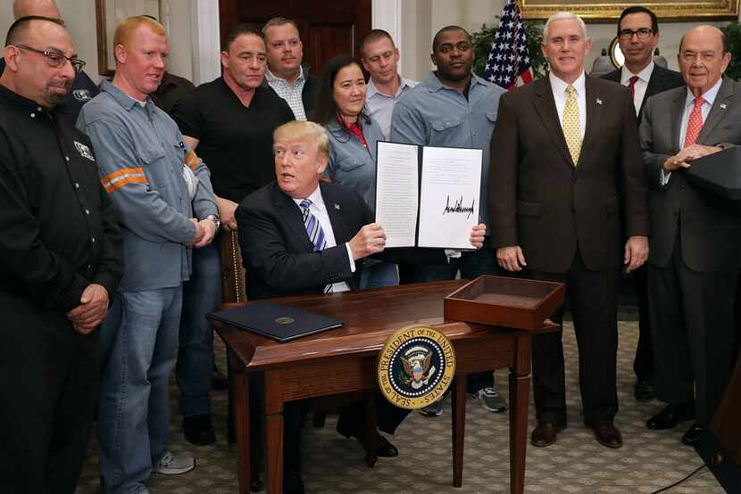 President Donald Trump holds up the "Section 232 Proclamation" on aluminum imports that he...