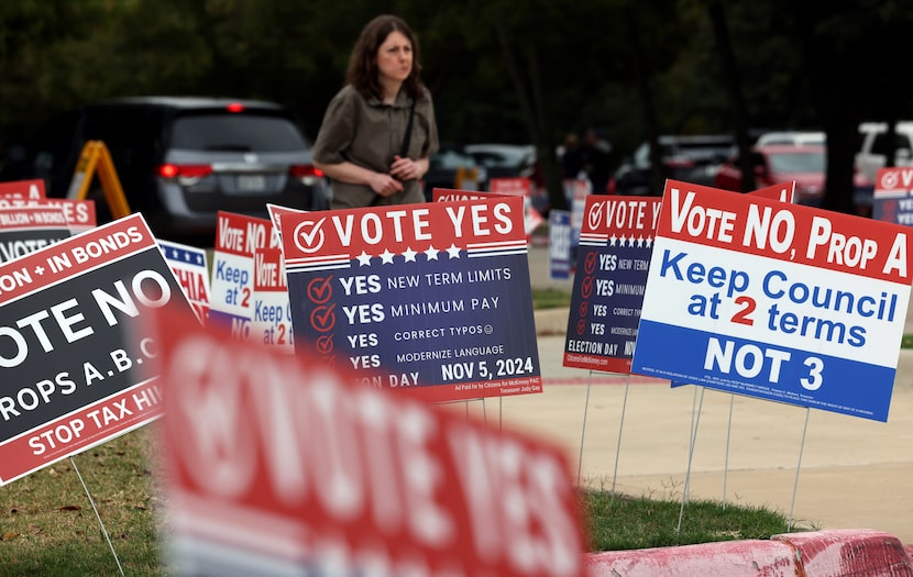 An area resident walks among a sea of campaign posters toward the parking lot during early...