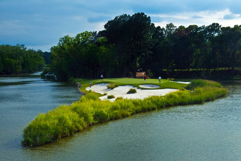 Golfers play the signature par 3, No. 15 green at Whispering Pines Golf Club in Trinity, TX,...