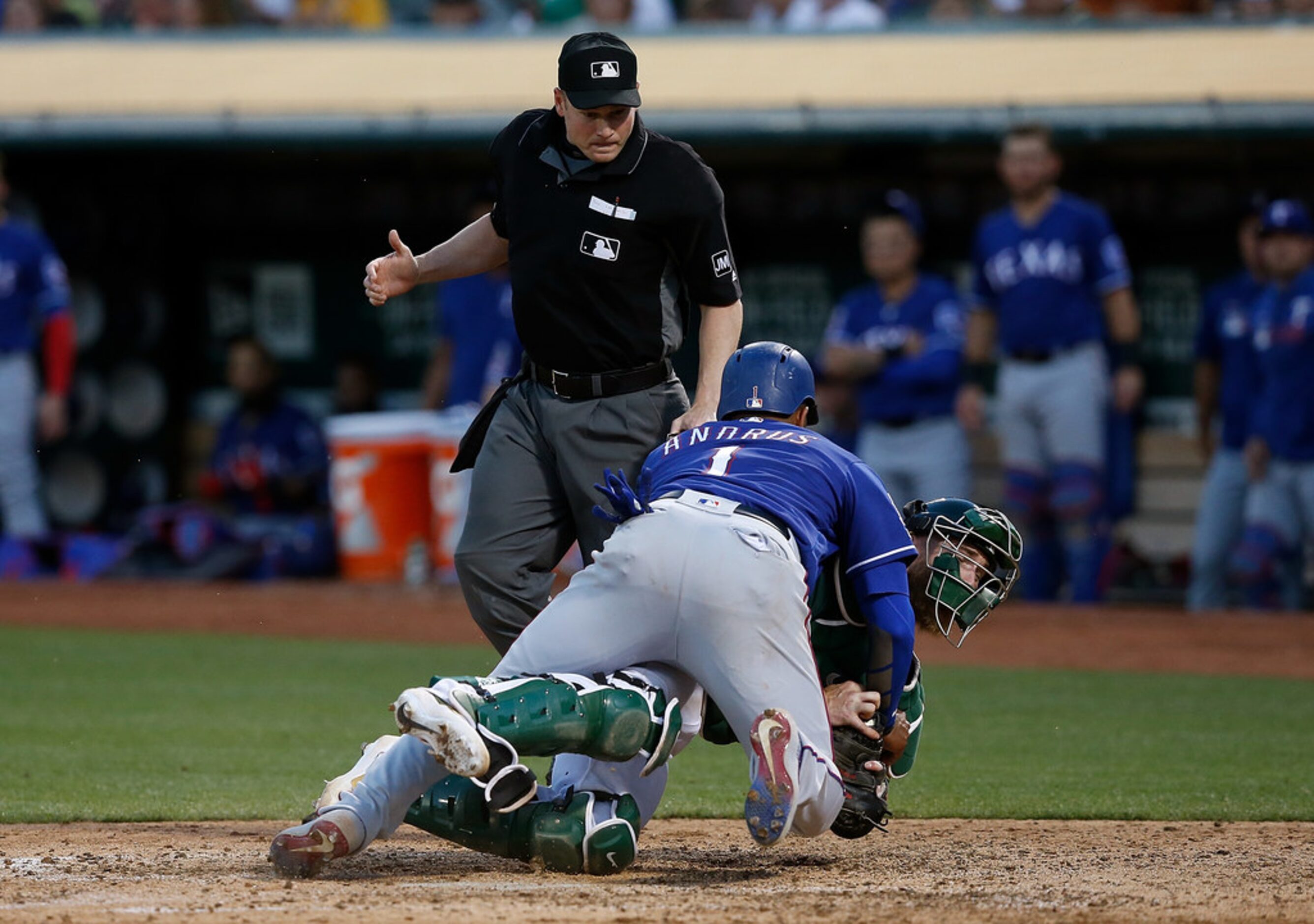 OAKLAND, CALIFORNIA - JULY 27: Elvis Andrus #1 of the Texas Rangers is tagged out at home...